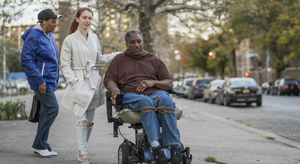 three people moving along sidewalk